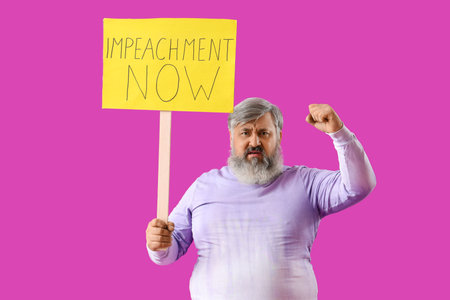 Protesting mature man holding placard with text IMPEACHMENT NOW on purple backgroundの写真素材