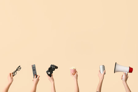 Hands holding popcorn, drink, game pad and 3D glasses on beige backgroundの写真素材
