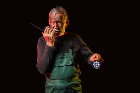 Mature miner man with two-way radio and flashlight on black backgroundの写真素材