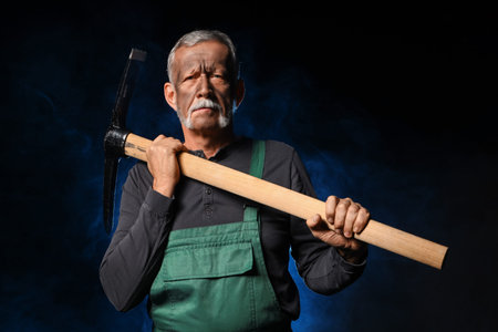 Mature miner man with pick ax and blue smoke on black background