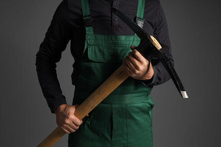 Mature miner man with pick ax on dark background