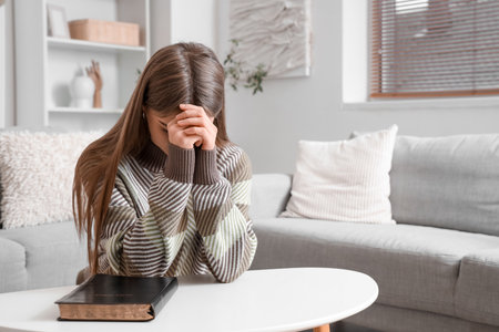Young woman praying near table at homeの写真素材