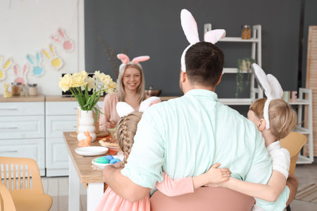 Little children hugging their father at Easter dinner in kitchen, back view