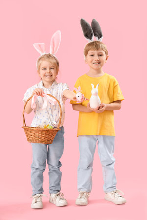 Little children in bunny ears with Easter eggs on pink background