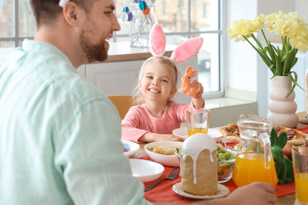 Cute little girl in bunny ears having Easter dinner at homeの写真素材