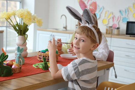 Cute little boy with his mother painting Easter eggs at home