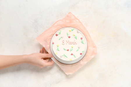Female hand with sweet bento cake on white background. International Women's Dayの写真素材