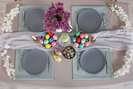 Festive table serving with painted eggs, flowers and burning candles for Easter celebration, top viewの写真素材