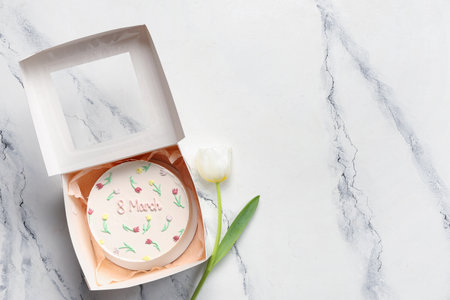 Box with sweet bento cake and beautiful tulip on white background. International Women's Dayの写真素材