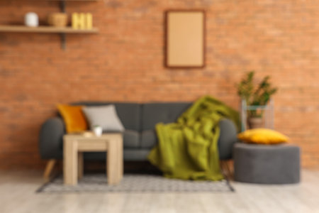 Loft style interior of living room with cozy sofa, pouf and table, blurred viewの写真素材