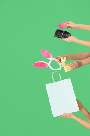 Women with payment terminal, credit card, bag and Easter decor on green background. Online shoppingの写真素材