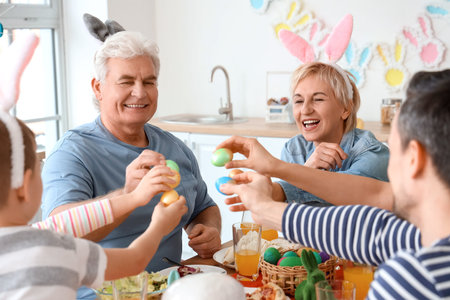 Happy family breaking Easter eggs at dinner in kitchen