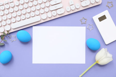 Easter eggs, flower, paper and computer keyboard on lilac backgroundの写真素材