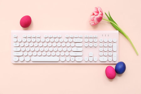 Easter eggs, flower and computer keyboard on pink background