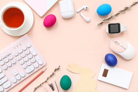 Frame made of Easter eggs, bunny, cup of tea, computer keyboard and mouse on pink background