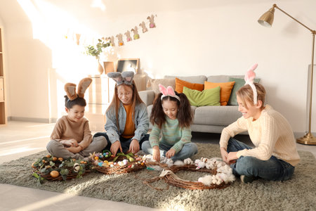 Little children in bunny ears making Easter wreaths at homeの写真素材