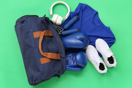 Sports bag with sportswear and boxing equipment on green backgroundの写真素材