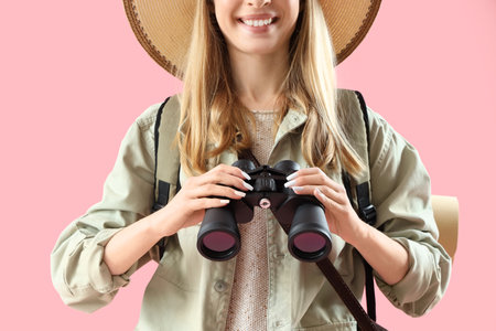Female traveler with binoculars on pink background, closeupの写真素材