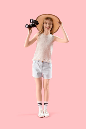 Young woman with binoculars on pink backgroundの写真素材
