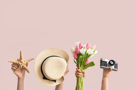 Female hands with straw hat, photo camera, starfish and flowers for International Women's Day on color backgroundの写真素材