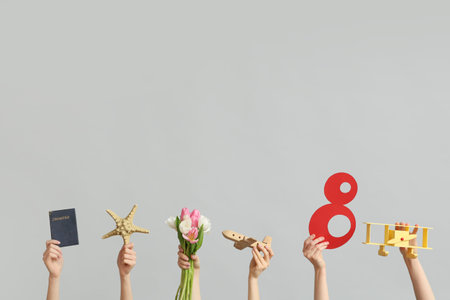 Female hands with paper figure 8, toy planes, passport and flowers for International Women's Day on...