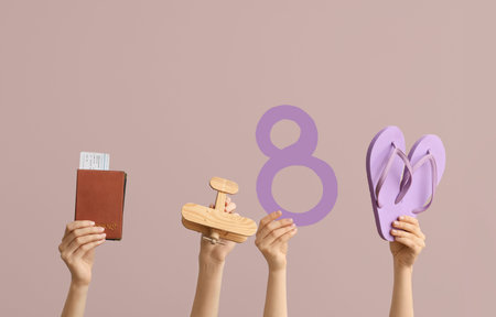 Female hands with paper figure 8, flip-flops, wooden plane and passport on color background....
