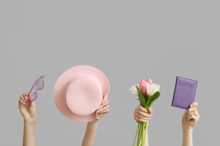 Female hands with beach accessories, passport and tulip flowers for International Women's Day on gray backgroundの写真素材