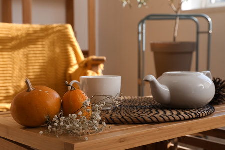 Pumpkins, tea set and flowers on wooden coffee table in living room, closeupの写真素材