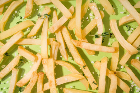 French fries with thyme and salt on green background