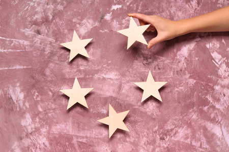 Female hand with five stars rating on pink grunge background. Customer experience concept