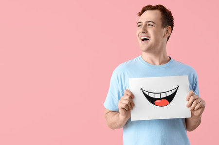 Young man with paper smile on pink backgroundの写真素材