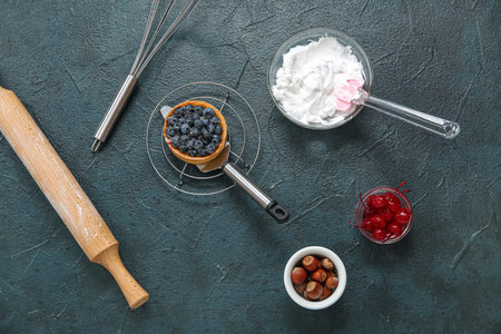 Grid with tasty cake and ingredients on black background