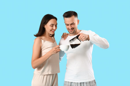Young couple pouring coffee on blue backgroundの写真素材