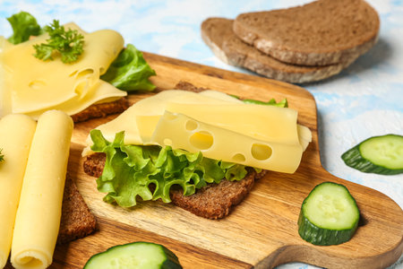 Tasty sandwich with cheese and lettuce in board on blue background, closeupの写真素材