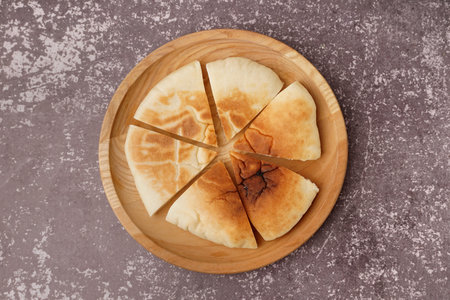 Plate with pieces of tasty pita bread on gray background
