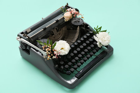 Vintage typewriter with beautiful flowers on color backgroundの写真素材