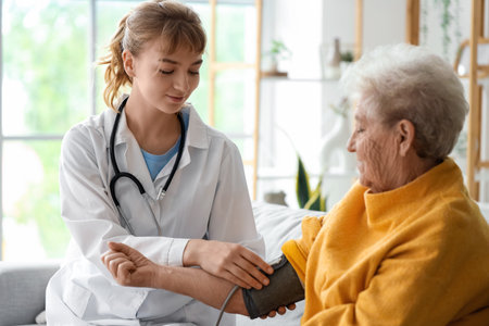 Doctor measuring blood pressure of senior woman at homeの写真素材