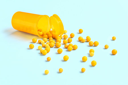 Jar with many yellow pills on turquoise backgroundの写真素材