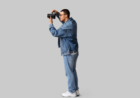 Male photographer with modern camera on gray backgroundの写真素材