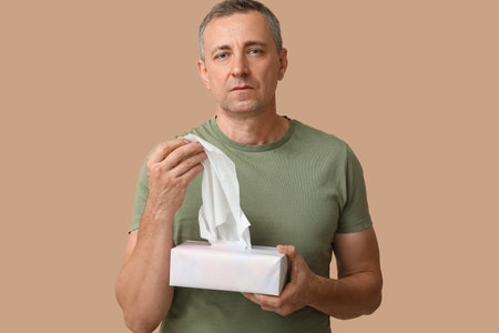 Ill mature man with tissues on brown background