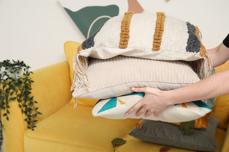 Woman putting stack of pillows on sofaの写真素材