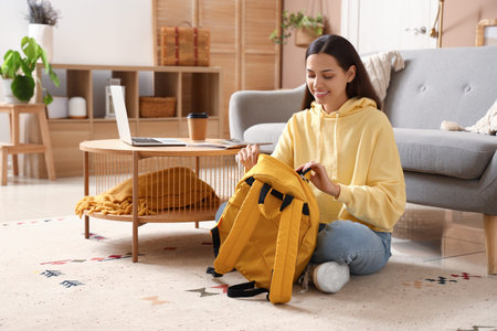Young woman in hoodie with backpack at home