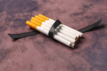 Cigarettes with black ribbon on grunge background. Lung cancer conceptの写真素材