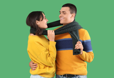 Happy young couple in warm clothes on green backgroundの写真素材