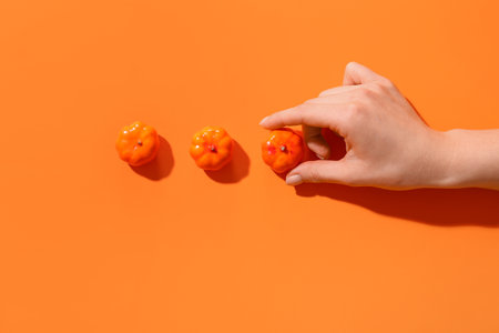Female hand with small pumpkins on orange backgroundの写真素材
