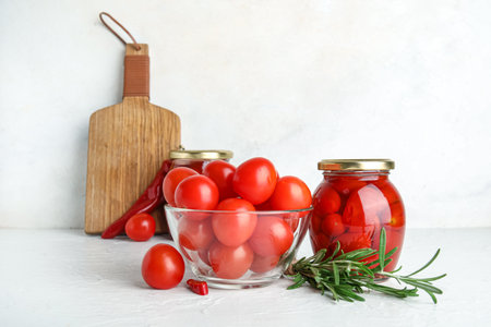 Jar of pickled tomatoes with rosemary and chili pepper on white backgroundの写真素材