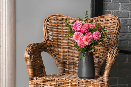 Vase of beautiful pink dahlias on wicker chair in living roomの写真素材