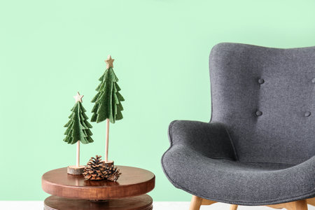 Gray armchair and Christmas decor on wooden table near green wallの写真素材