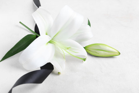 Beautiful lily flowers with funeral ribbon on white backgroundの写真素材