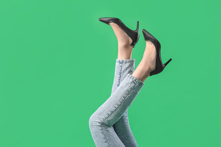Legs of young woman in stylish black high heels on green backgroundの写真素材